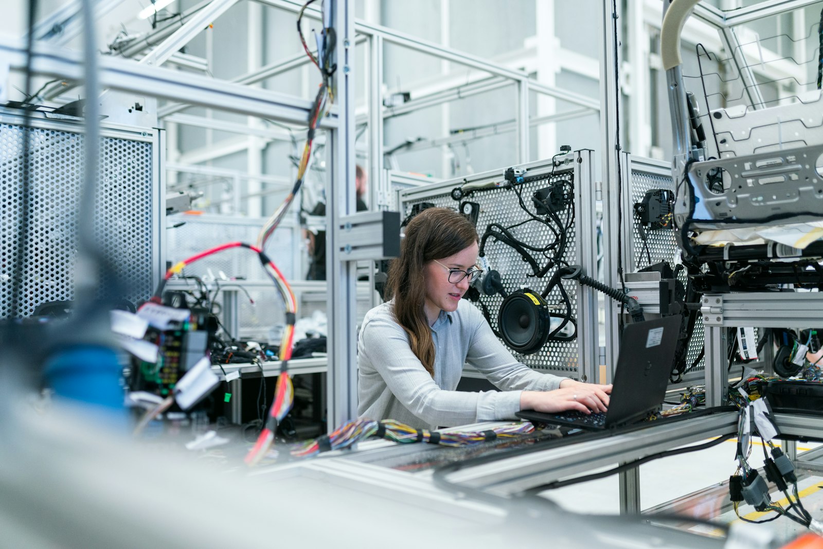 Engineer working with a complex hardware test rig and a laptop — building a small focused tool that fits.