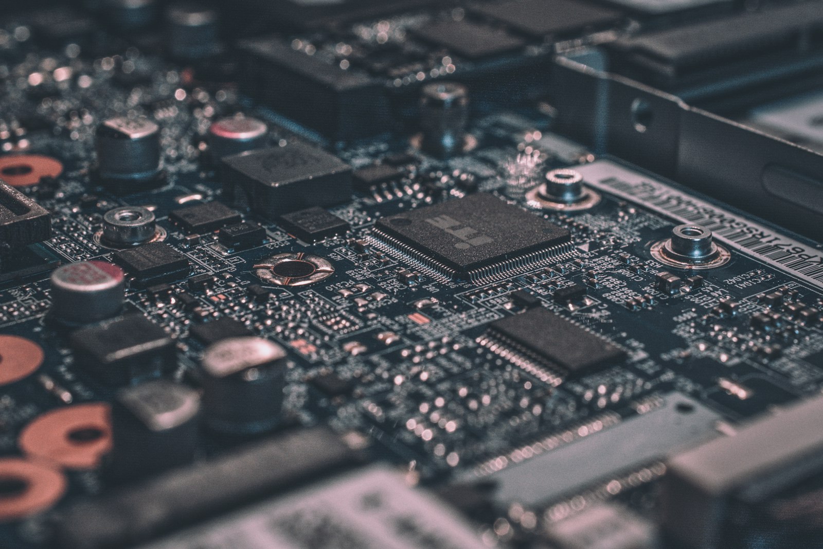 Macro of a circuit board with warm metallic capacitors and a precision-soldered chip — the technical infrastructure underneath AI, automation and internal tools.