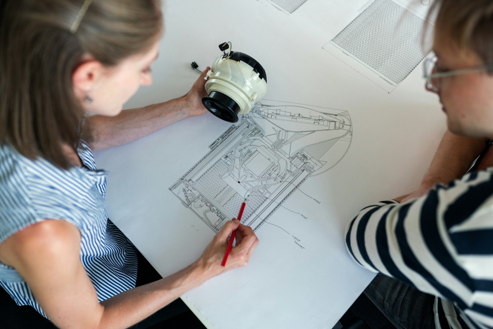 Engineers working over a technical blueprint with a precision-engineered part — process design and automation.