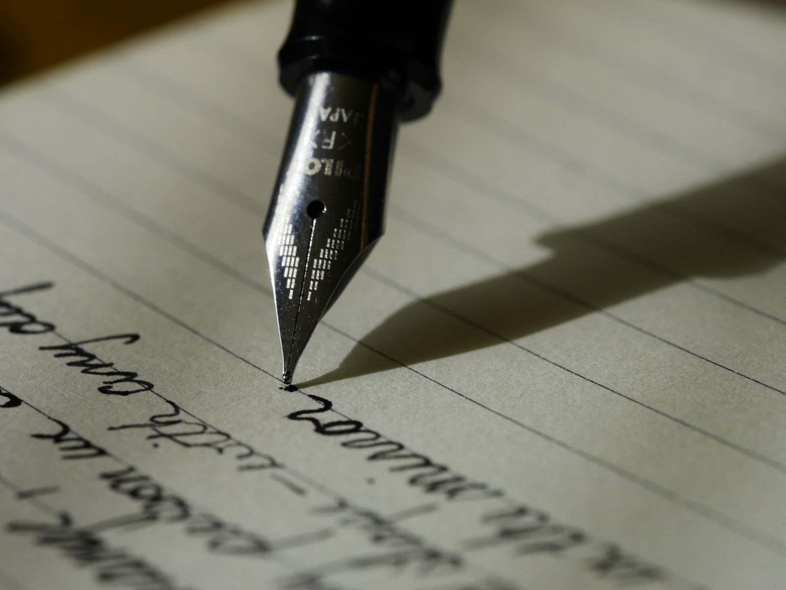 Close-up of a fountain pen writing on a lined notebook — deliberate, hands-on planning rather than slide-deck strategy.